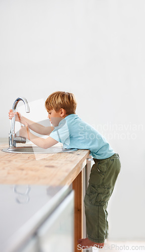 Image of Children, fantasy and a child in the kitchen sink, playing a game in his home as a plumber character. Kids, basin and counter with a curious young boy in a modern apartment for imaginary plumbing