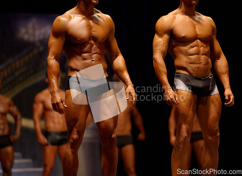 Image of Man, fitness and line of professional bodybuilder on stage for sports, judge or competition. Male person or muscular group of models standing in confidence, underwear or lingerie for contest