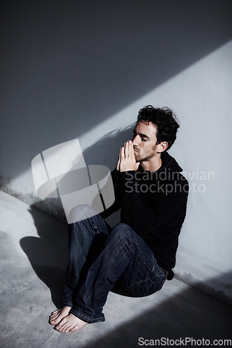 Image of Man, sad or depression with mental health and pray, stress or burnout, thinking of financial crisis with worship and help. Emotional, praying hands and trauma, bankruptcy or debt with wall background