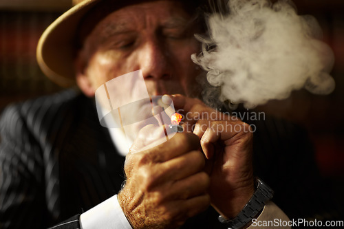 Image of Mature, man and cigarette with lighter for smoking to relax in space. Elderly person, mob boss or gangster with suit, hat and serious face for habit, hand and puff for meeting in criminal activity