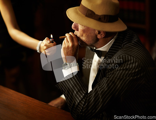 Image of Businessman, mafia and hold for cigarette in office with woman for light. Gangster, mob or person in suit, bowtie and hat for meeting, criminal activity or job with tobacco for relaxation in space