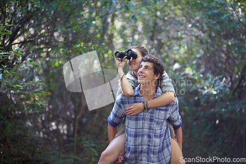 Image of Man, woman and piggyback outdoor with binocular for travel, adventure or sightseeing in nature with happiness. Couple, people and tourist hiking in woods or forest for experience, holiday or vacation