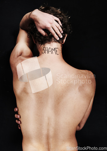 Image of Back, shame tattoo and nude man in studio isolated on a black background. Rear view, regret and body of person embarrassed at mistake, fail and abuse crisis, depression and mental health challenge