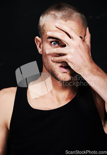 Image of Portrait, anxiety and man peek through hands in studio isolated on a black background. Face, scared and person peep through fingers, spy or paranoid at horror, fear danger or stress for mental health