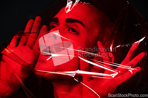 Image of Man, red plastic and suffocating in studio isolated on black background. Polyethylene, film or person with depression, social isolation and anxiety, stress or mental health crisis, psychology or neon