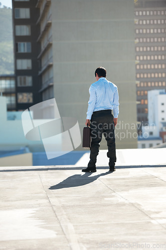 Image of Businessman, suicide and rooftop with stress, depression and mental health with suitcase outdoor in city. Professional, person or employee and back on roof of building with anxiety, risk and crisis