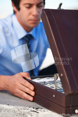 Image of Businessman, person and briefcase with money with corruption, thief and fraud outdoor for financial crisis. Professional, man and face with contemplation for cash, finance and secret with stress