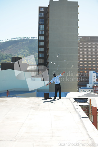 Image of Back, financial freedom and money rain with a man in the city, throwing cash during a summer day. Finance, success or raining dollars with a business person on the roof of a building in an urban town