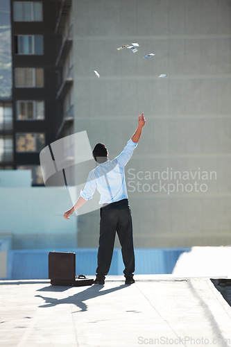 Image of Back, financial freedom and money rain with a businessman in the city, throwing cash during a summer day. Finance, success or raining dollars with a person on the roof of a building in an urban town