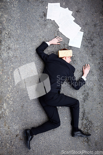 Image of Death, accident and brick on a business man lying on a street in the city from above for financial crisis. Ground, documents and mistake with a young employee crippled by debt in a recession