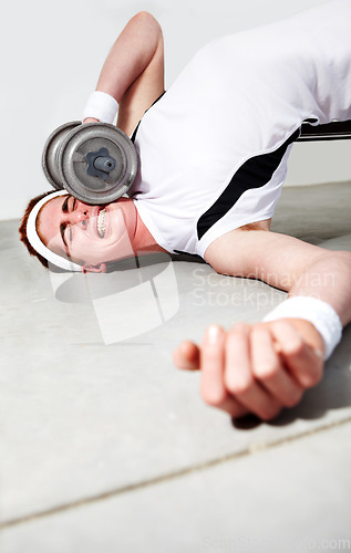 Image of Fitness, face and dumbbell with an unlucky man in the gym after an accident while lifting heavy weights. Exercise, injury or pain with a young person making a mistake during a training workout