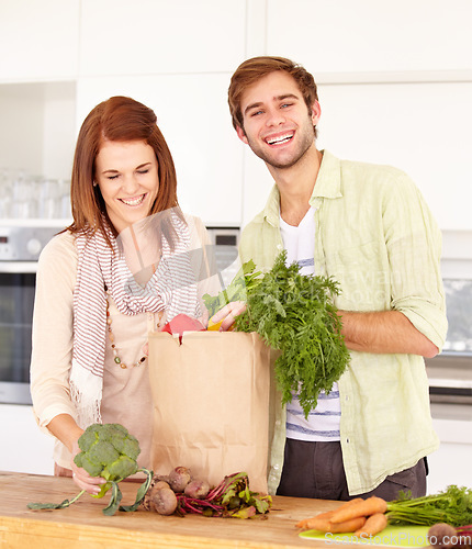 Image of Couple, kitchen and vegetables for grocery shopping, unpacking and smile for food, nutrition and cooking. Man, woman and healthy in home, vegan, diet and package for vegetarian, produce and fresh