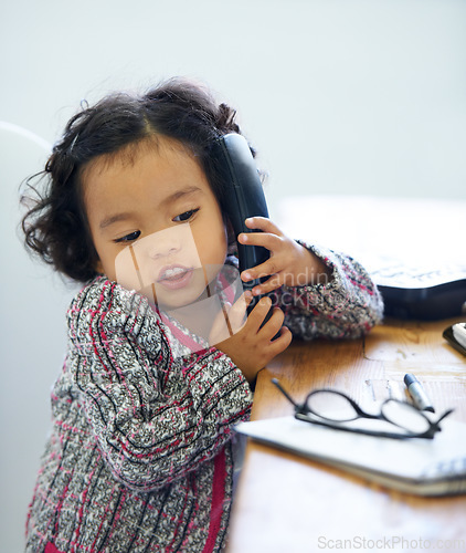 Image of Playing, talking and a child on a telephone for communication, pretend work and cute. Sitting, house and a girl, kid or a baby speaking on a landline phone for play, imagination or discussion