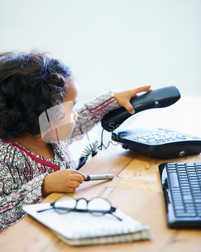 Image of Playing, child and a telephone for a phone call at a desk for communication, pretend work or childhood. Playful, table and a girl, kid or baby with a landline for conversation, contact or secretary