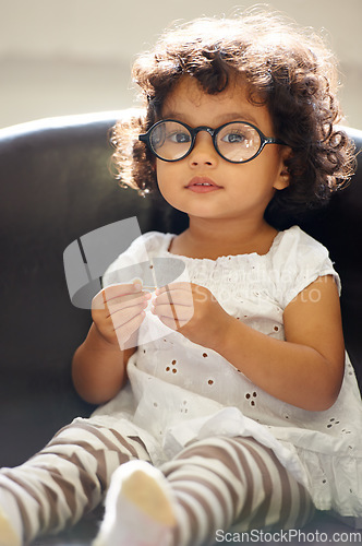 Image of Girl, child and portrait or glasses for play, learning development or education growth. Female person, toddler and face eyewear on sofa in home for comedy outfit as professional, intelligence or fun