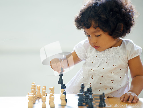 Image of Toddler, girl and chess play for learning growth, childhood development or thinking challenge. Female person, board game or table problem solving intelligence or kids, planning knowledge or education