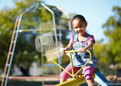 Image of Girl child, smile and seesaw at park, school or outdoor in spring for playful games, adventure or freedom. Kid, playground and happy in kindergarten, nature and summer sunshine with thinking by trees