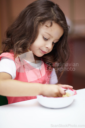 Image of Girl child, bowl and eating at kindergarten with thinking, nutrition and learning with food on desk. Kid, diet and hungry at table for wellness, health and ideas at lunch, relax and preschool class