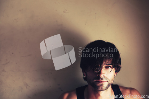 Image of Portrait. space and a messy model in studio on a wall background for marketing or advertising. Face, mockup and a confident young man looking serious, cool or moody on a backdrop with shadow