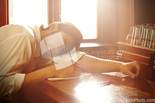 Image of Notebook, man and sleeping in bar or writing for journalist and media freelance career. Fatigue, exhausted and tired person, drink or author with glasses and notes or sunlight on table to nap or rest