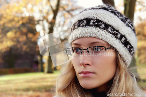 Image of Face, thinking and glasses with a woman in the park during an autumn or winter morning to relax. Idea, fashion or beanie and a young person in a garden outdoor to view nature with blurred space