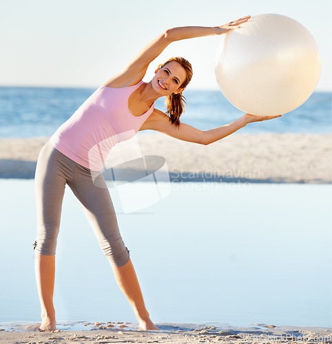 Image of Woman, exercise ball and stretch for pilates on beach for fitness, health or wellness in portrait. Female instructor, trainer and smile on face in meditation, calm or balance in peace, zen or relax