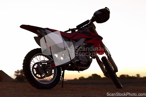 Image of Dirt, bike and sunset in desert for action danger competition, fast race or speed training. Off road, motorcycle and helmet outdoor for fearless brave adventure, adrenaline or extreme sport transport