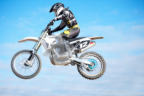 Image of Person, motorcycle and air jump in blue sky as professional in action, competition or fearless. Bike rider, off road transportation stunt or fast speed adventure at rally, extreme sport or challenge