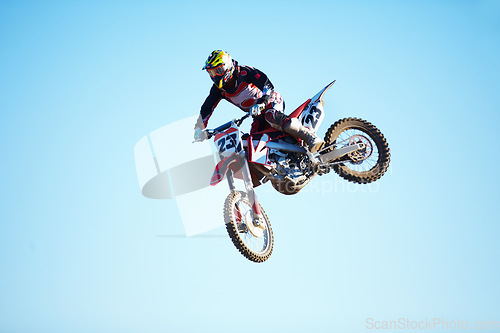 Image of Person, motorcycle and jump adventure in blue sky as professional in action, competition or fearless. Bike rider, off road race or air stunt for speed driving at rally, extreme sport or challenge