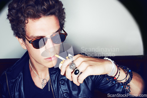 Image of Portrait of man with cigarette, rock fashion and rockstar attitude on white background in spotlight. Cool punk style, grunge and smoking, confident and handsome male model in studio with sunglasses