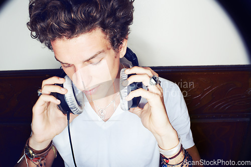 Image of Man with headphones, rock dj and audio beats with rockstar attitude on white background with spotlight. Cool punk style, grunge sound and music, club culture with male model listening to earphones.