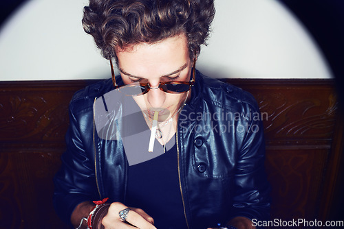 Image of Man with cigarette, punk in sunglasses and rockstar attitude on white background with spotlight. Cool rock style, grunge fashion and smoking, confident and handsome male model in studio with freedom.