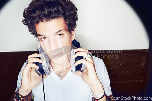 Image of Portrait of man with headphones, rock dj and beats with rockstar attitude on white background with spotlight. Cool punk style, sound and music, club culture with face of male model with entertainment