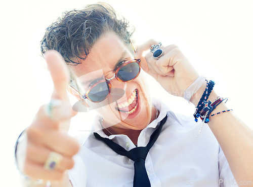 Image of Man, gun finger and portrait with sunglasses, crazy and sign language for punk attitude by white background. Rock person, shouting and shooting with vintage jewelry, edgy clothes and point at you