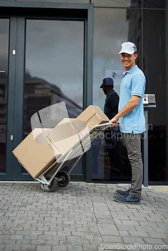 Image of Box, portrait or trolley with a happy delivery guy by office for entrance for online shopping or product. Apartment, hand truck or courier man with stock by a home for ecommerce service or package