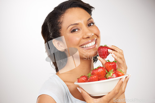 Image of Happy, strawberries and portrait of woman in a studio for wellness, nutrition and organic diet. Smile, vitamins and young female person eating a fruit for healthy vegan snack by gray background.