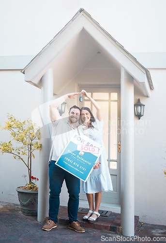 Image of Young caucasian couple holding house keys while moving into new apartment. Happy man and woman holding for sale and sold sign outside home while relocating. Securing a loan for property or real estat