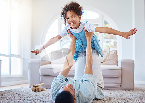 Image of Adorable smiling mixed race girl bonding with her single father in a home living room. Hispanic man playing games and lifting his daughter into the air. Happy child enjoying a weekend with her parent