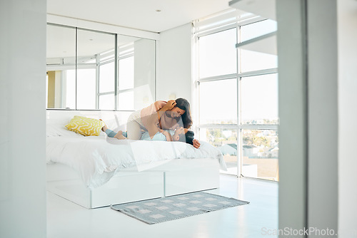 Image of Happy playful young mixed race woman kneeling on top of her boyfriend in bed at home. Romantic couple bonding in their bedroom in the morning. Carefree boyfriend and girlfriend laughing while intimat