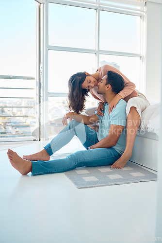 Image of Full body young mixed race couple sitting together and bonding in their bedroom at home. Hispanic woman on a bed touching and leaning in to kiss her asian boyfriend in their apartment. Happily in lov