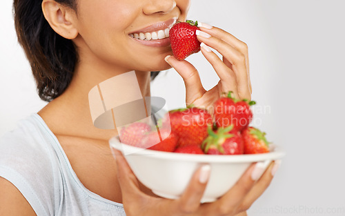 Image of Health, strawberries and closeup of woman in a studio for wellness, nutrition and organic diet. Smile, vitamins and zoom of female person eating a fruit for healthy vegan snack by gray background.