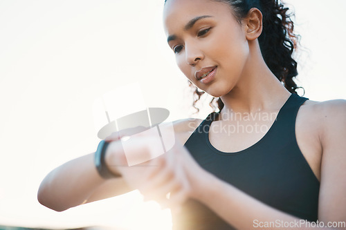 Image of Whats my time looking like. an attractive young female athlete checking her smartwatch while out for a run in the city.