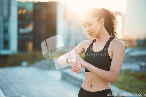 Image of Ive got some time to spare. an attractive young female athlete checking her smartwatch while out for a run in the city.