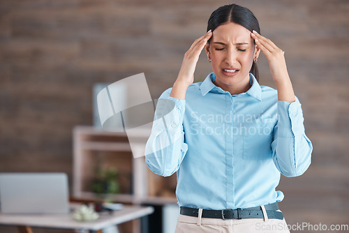 Image of Beautiful mixed race business suffering with a headache while standing in her office. Young corporate worker struggling with a migraine while at work. The stress and anxiety of deadline pressure