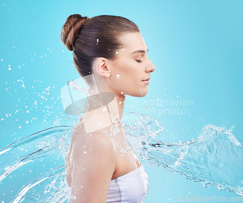 Image of Glowing skin, a gift from your shower. a beautiful young woman being splashed with water against a blue background.