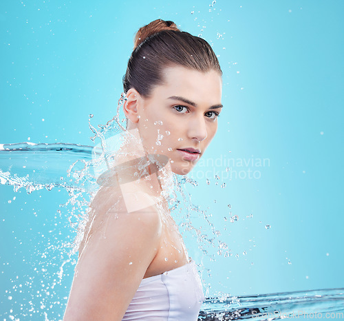 Image of Feeling like the greatest. a beautiful young woman being splashed with water against a blue background.