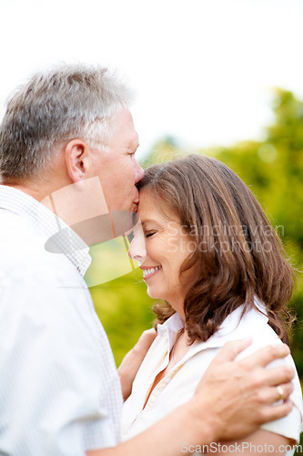 Image of Senior man, kissing and wife on forehead in park, care and people love for commitment in marriage. France, couple and wellness in nature to connect, hug and happy together in support family on date