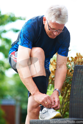 Image of Senior, tie or runner with shoes on bench in nature for exercise, training or fitness workout. Start, healthy man or mature athlete in park with sports footwear ready for jog, walking or wellness