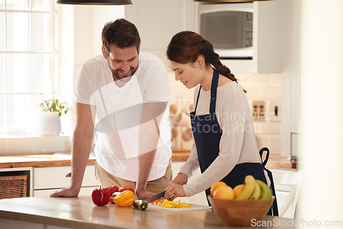 Image of Whats on the menu. a man watching his wife as she prepares a meal in the kitchen.