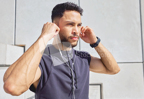 Image of Im all in. a sporty young man listening to music while exercising outdoors.